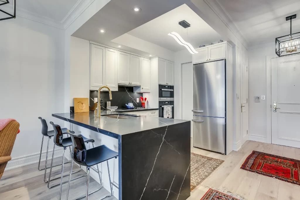 Modern condo kitchen renovation with marble island and white cabinetry in Toronto
