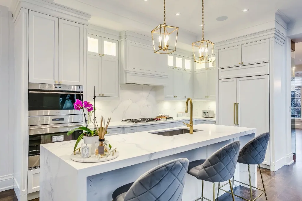 White kitchen renovation with marble waterfall island and brass lantern pendants in Lawrence Park, Toronto